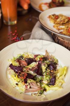 Healthy vegeterian food on brown wood board. Spring vitamin dieting food. Salad from beet with dried tomatoes and cabbage
