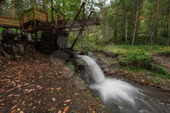 Rustic watermill with wheel being turned by force of falling water from Altai mountain river. Slow shutter speed.