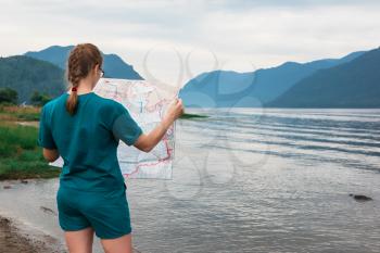 Woman with map on Teletskoye lake in Altai mountains, Siberia, Russia.