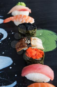 Various kinds of sushi served on wood black table.