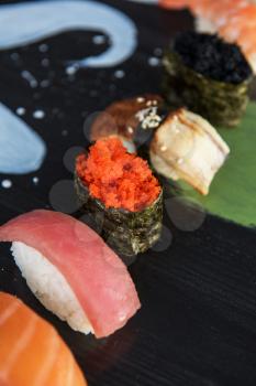 Various kinds of sushi served on wood black table.