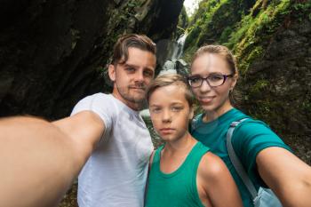 Selfie of family on the waterfall background in Altai mountains, Siberia, Russia. Beauty summer day.