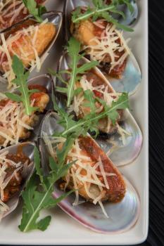 Cooked mussels with sauce cheese and arugula