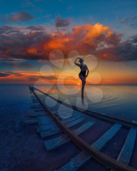 Woman at beauty sunset on salty lake with railway, concept of vacation at home, local tourism or domestic tourism
