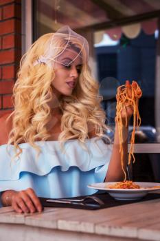 Food, people and leisure creative concept - beauty blonde young woman eating pasta in cafe