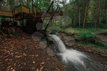Rustic watermill with wheel being turned by force of falling water from Altai mountain river. Short shutter speed.