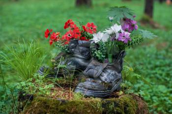 Touristic boot with flowers in the forest. Summer background with forgotten boots and wild flowers. Concept of summer season and traveling.