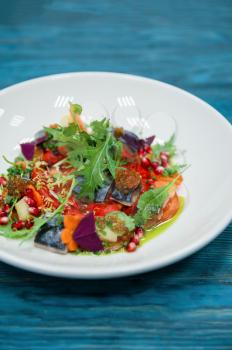 Escabeche fish dish with caviar: mackerel in marinade with vegetable, on a plate on the wooden blue background.