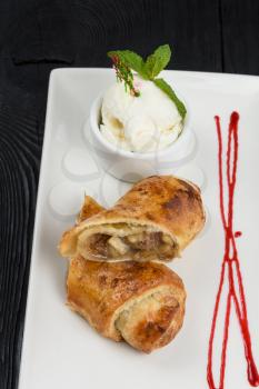 Apple strudel with vanilla ice cream decorated with caramel and berries sauce