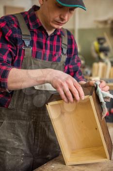 Carpenter painting wooden board in a wooden workshop. Profession, carpentry and woodwork concept.