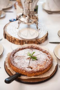 Apples pie with samovar on the served table
