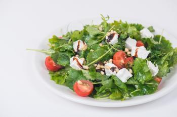 Green salad with vegetables: greens, arugula, tomato, cheese, pine nuts and sauce