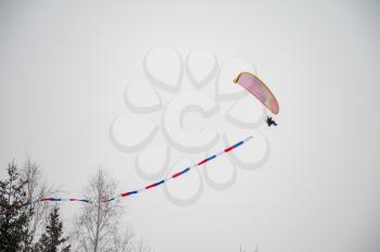 Paraglider is flying in the sky in the Altai winter mountains.
