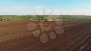 Aerial drone view of agriculture machinery on spring field