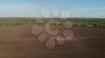 Aerial drone view of agriculture machinery on spring field