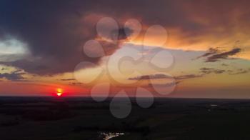 Aerial view from high attitude of sunshine dramatic sky. Sunset scenic sky above summer field and meadow in evening. Hyperlapse