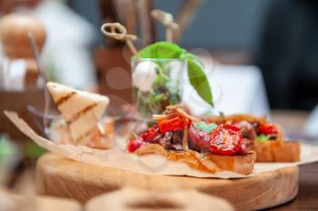 Tasty tomato Italian bruschetta on toasted slices of baguette with spice herbs and basil on a wooden board. Catering concept