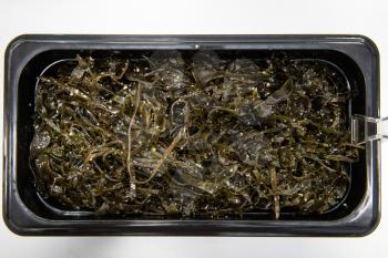 Chuka wakame laminaria seaweed salad in plastic bowles. Concept of healthy food production or delivery food
