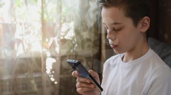Handsome teen or young boy at home with smartphone