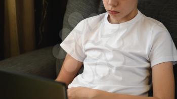 Handsome teen or young boy at home with laptop. Concept of home remote learning or school homework
