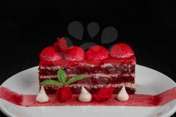Plate with piece of delicious red velvet cake on black wooden background, food and drink concept
