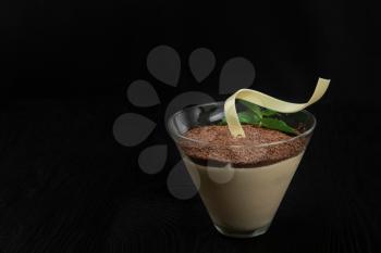Delicious Italian dessert tiramisu, on a black wooden background decorated with mint leaf, with copy space.