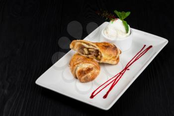 Apple strudel with vanilla ice cream decorated with caramel and berries sauce