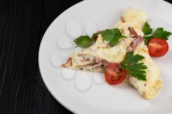 Omelet with Ham and Cheese on black wooden background