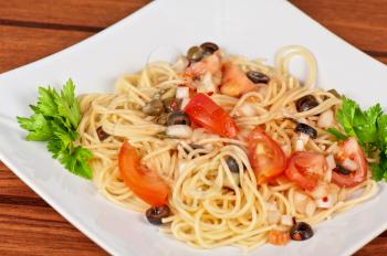 Pasta with tomato, black olives, capers and greens