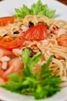 Pasta with tomato, black olives, capers and greens