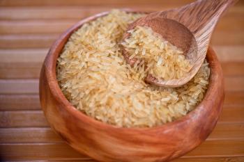 golden rice on wooden plate on wooden background