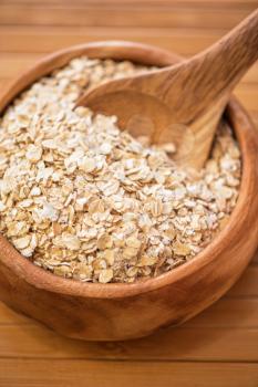 Oat flakes at wooden plate on wooden background