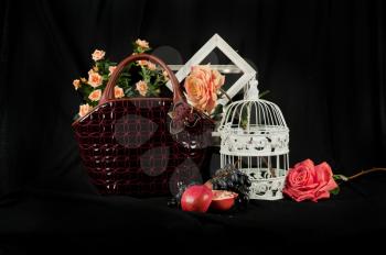 Fashionable handbag  with cage fruits and flowers on black background. 