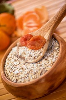 Oat flakes with  dried apricots at wooden plate on wooden background