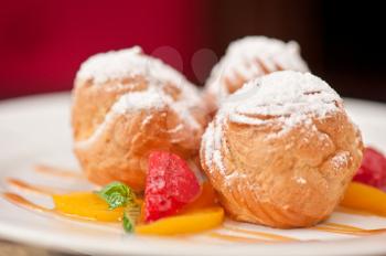 profiteroles from cream and condensed milk decorated with strawberry and peach