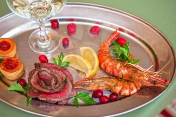 Grilled shrimps and beef meat on a plate