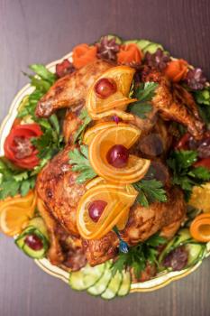 Whole roasted chicken with vegetables and fruits on wooden table