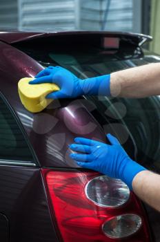 hand with sponge over the car for washing