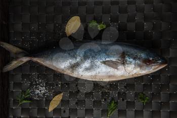 raw tuna fish with salt and spices on black background