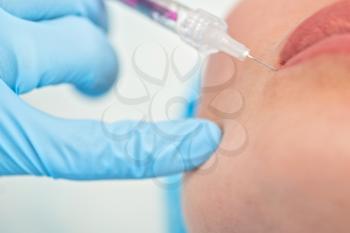 Closeup of woman gets injection in her lips