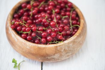 Fresh red currants in plate on wooden table