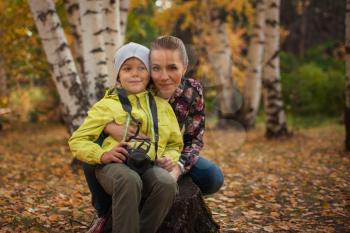 Woman and her son with camera in autumn forest
