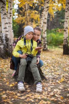 Woman and her son with camera in autumn forest