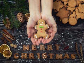Woman hands keep gingerbreads for new years and christmas on wooden background with space for design