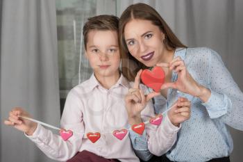 Happy Valentines Day or Mother day. Young boy spend time with her mum and celebrate with gingerbread heart cookies on a stick.