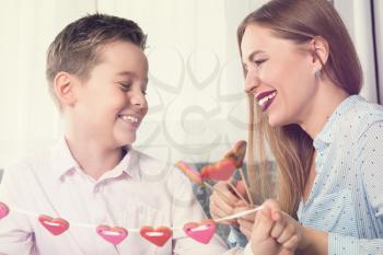 Happy Valentines Day or Mother day. Young boy spend time with his mum and celebrate with gingerbread heart cookies on a stick.