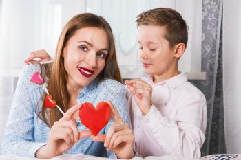 Happy Valentines Day or Mother day. Young boy and mum celebrate with gingerbread heart cookies on a stick.
