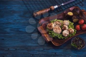Grilled mushrooms champignons with vegetable on a blue wooden background