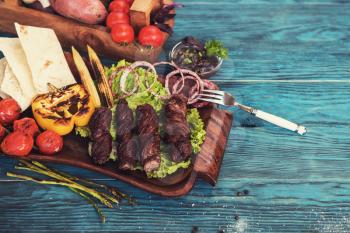 Grilled lamb meat with vegetable on a blue wooden background