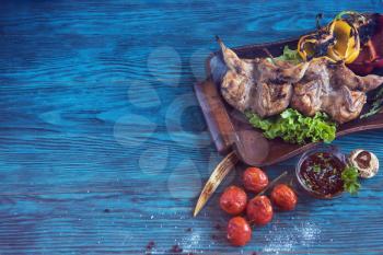 Grilled quail meat with vegetable on a blue wooden background